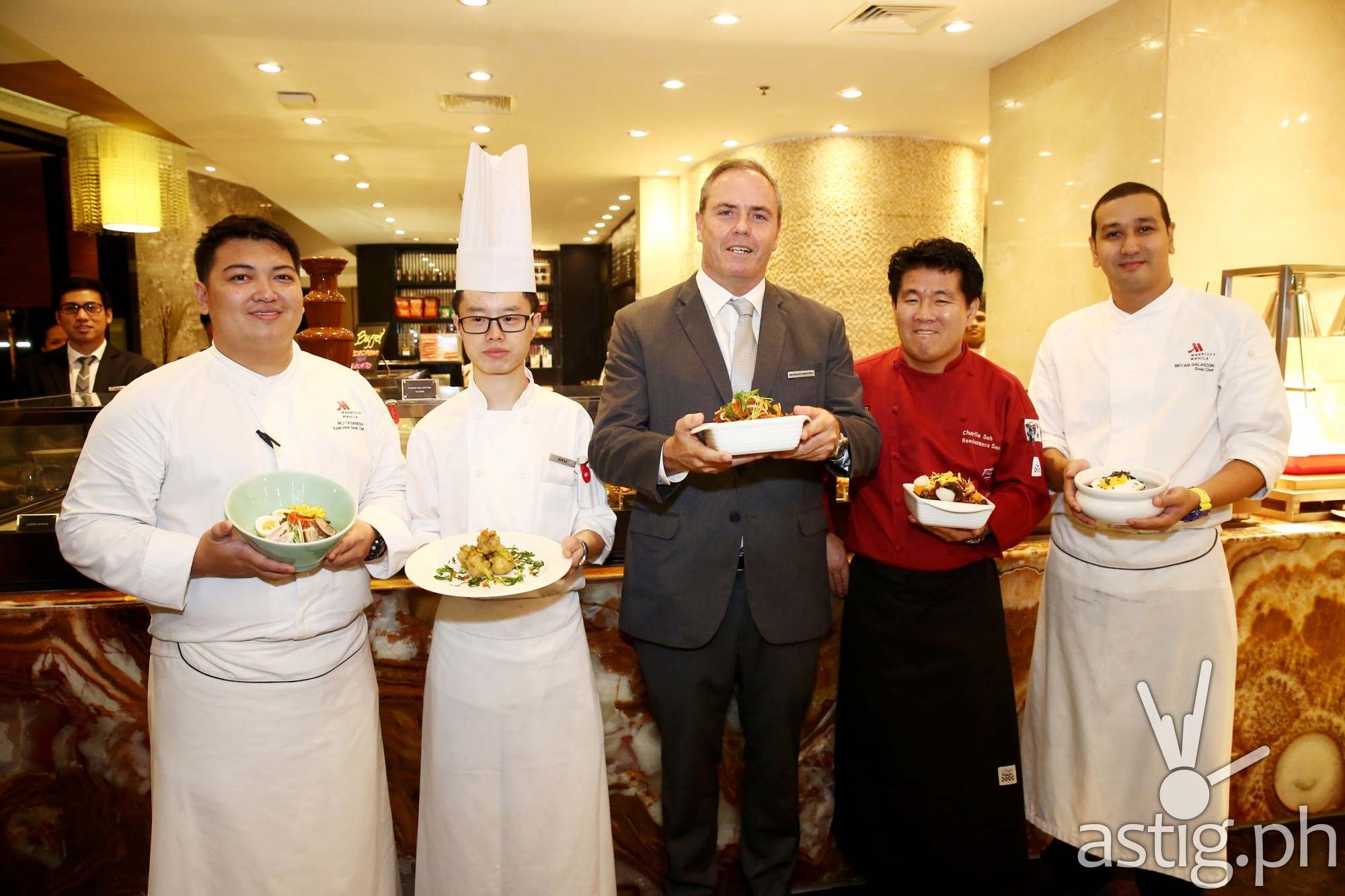 A unique celebratory “cheers” of the best authentic Asian dishes by Executive Sous Chef Rej Casanova holding a Ramen Bowl, Chinese Sous Chef Jun Li holding boneless chicken with wasabi, Director of Food and Beverage Brendan Mahone