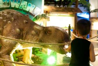 Kid touching animatronic dinosaur -Dinosaurs Around The World exhibit - Mind Museum BGC